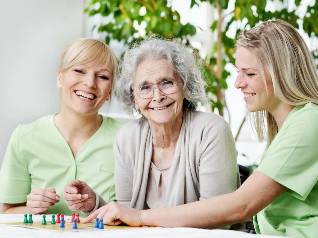Jasmine Estates of Edmond | Senior woman and her two caregivers playing a game