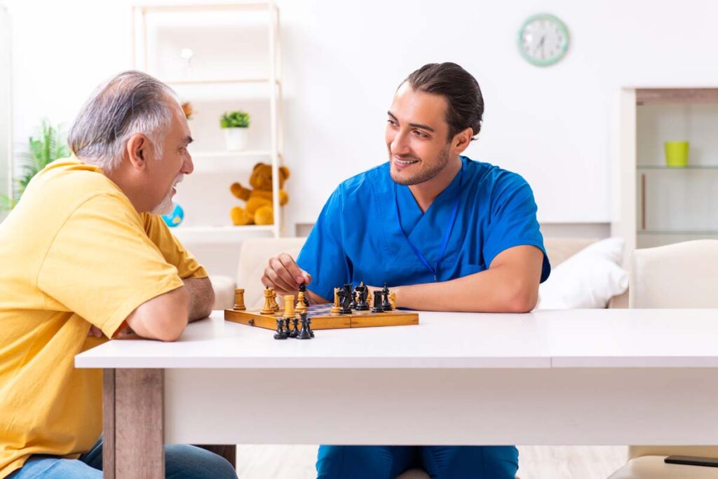Jasmine Estates of Edmond | Caregiver playing chess with senior